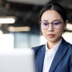 Focused asian businesswoman working on a laptop in a modern office environment
